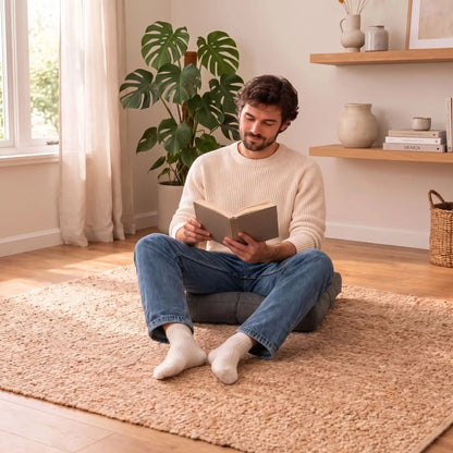 homme lisant dans une posture détendue sur gros coussin de sol